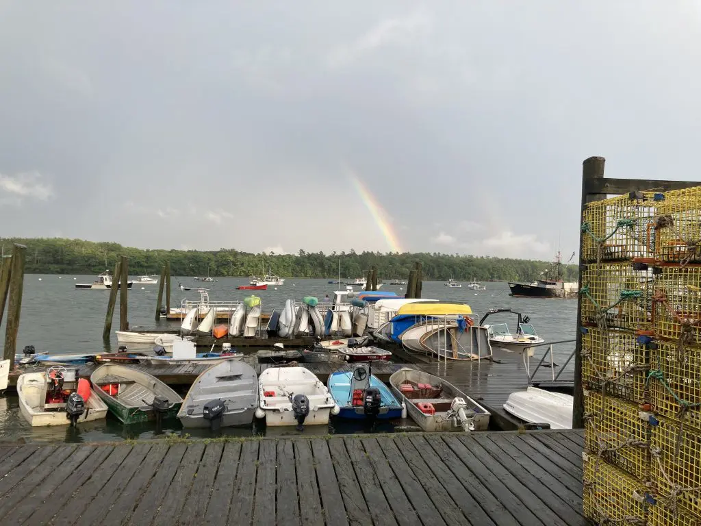 amazing rainbow seen from the end of the wharf with small boats in the foreground